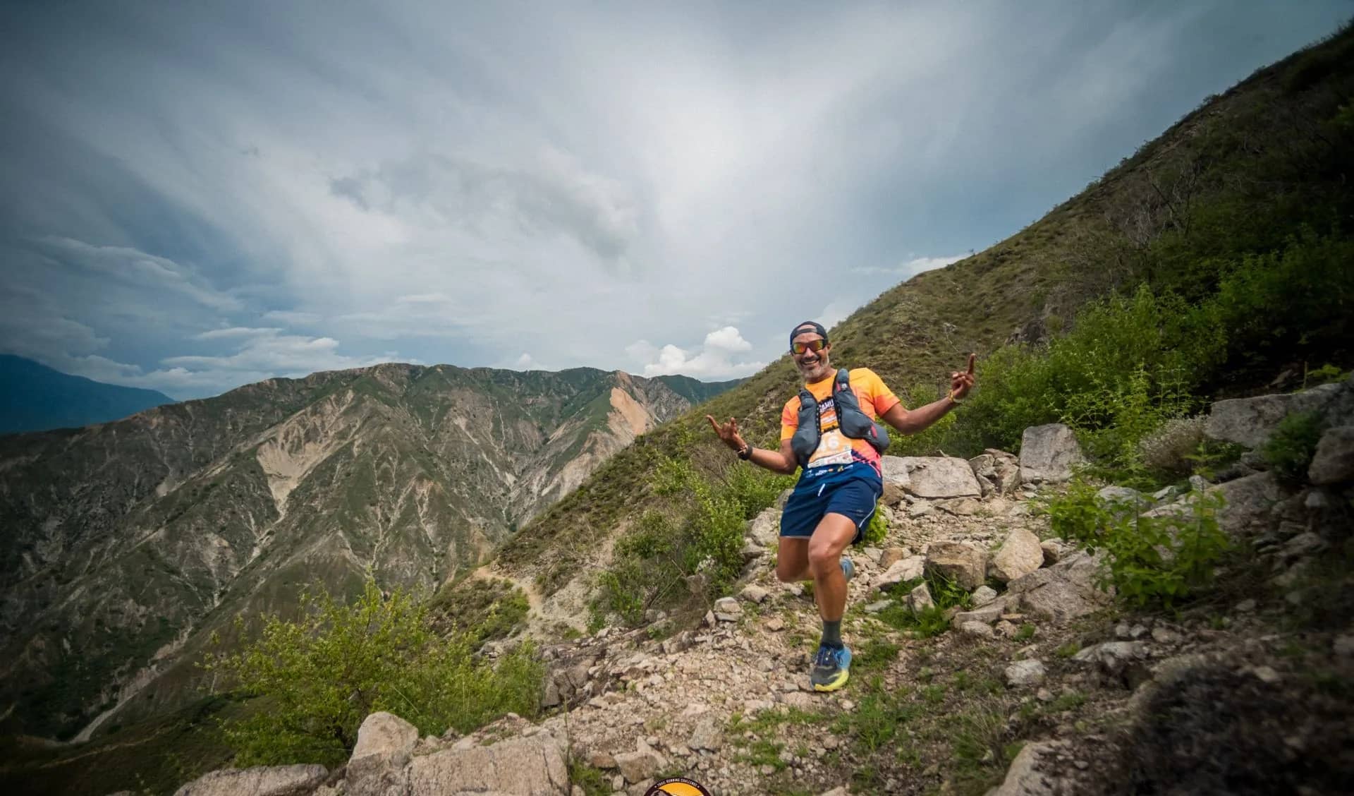 Corredor en un sendero de piedra con las laderas del cañón y nubes de tormenta al fondo
