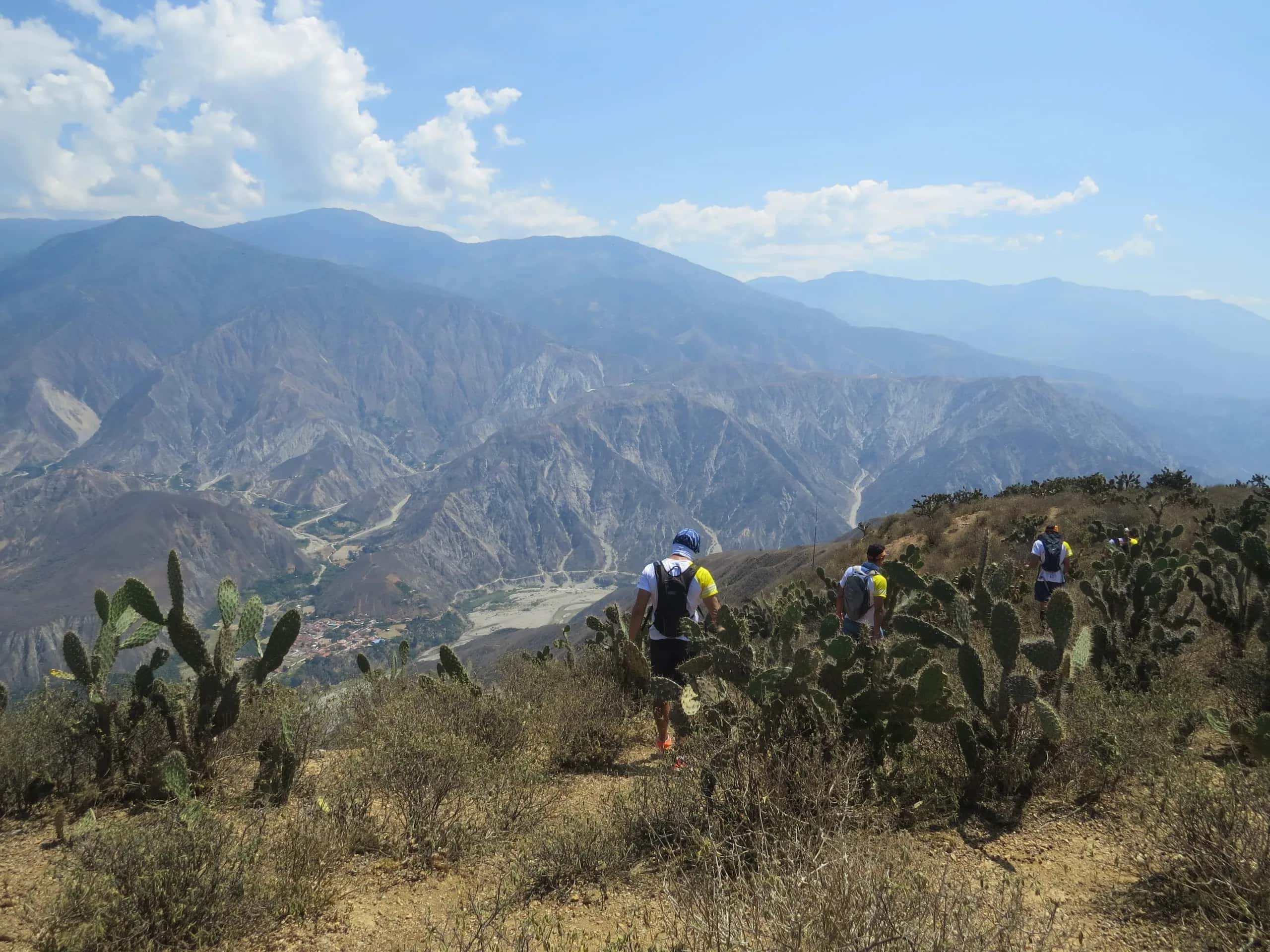 Corredores entre cactus en el borde del Cañón del Chicamocha, con las montañas azules al fondo